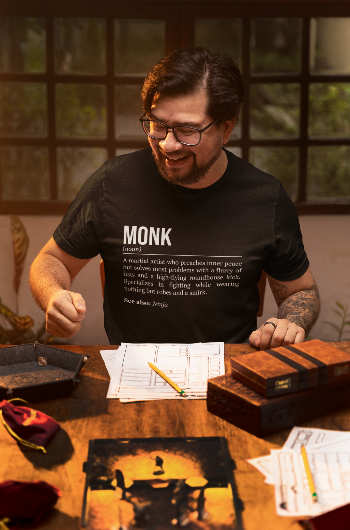 A man playing an RPG at a table, wearing a black monk T-shirt showing the definition of the class Monk.
