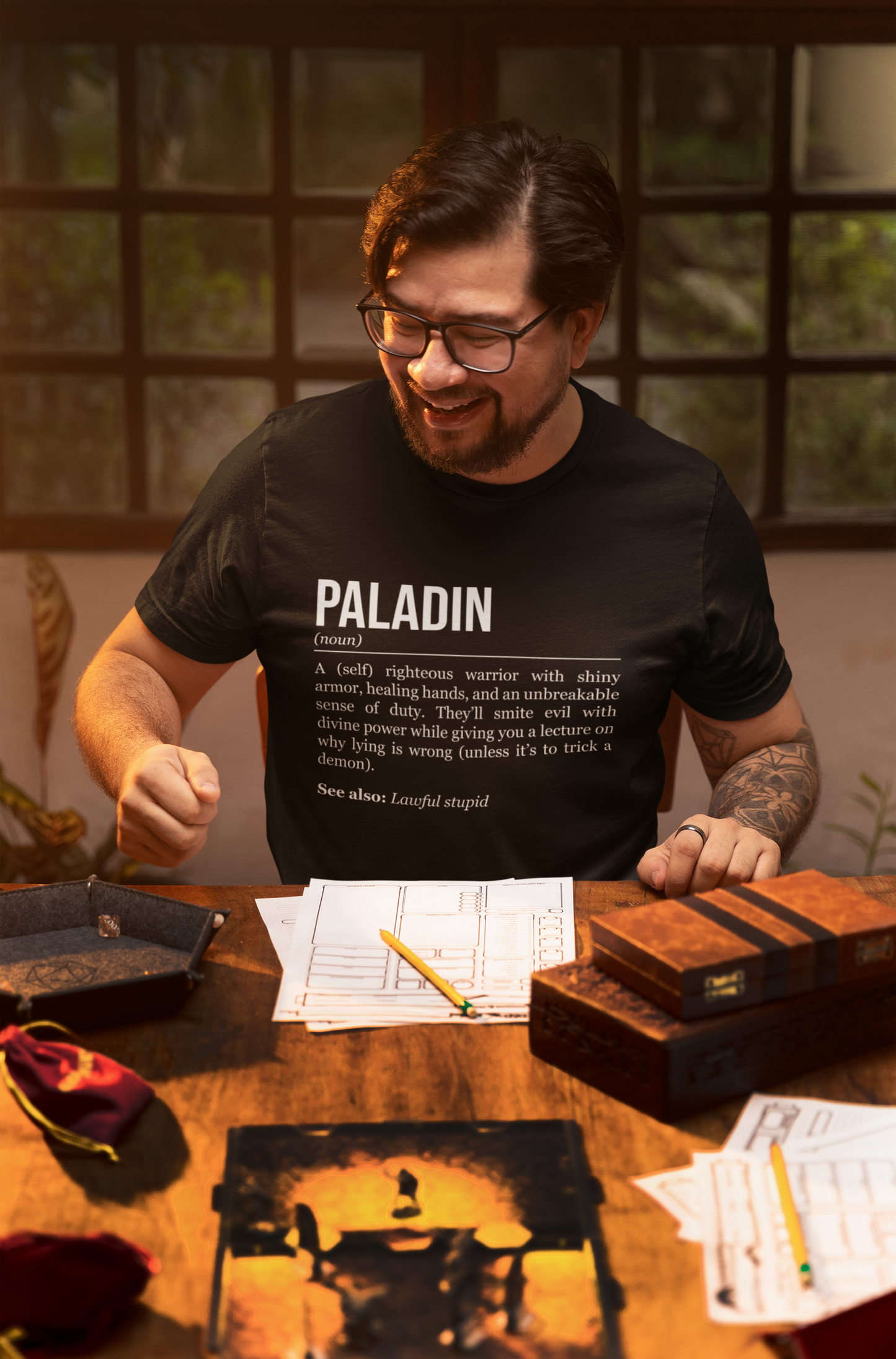 A man playing an RPG at a table, wearing a black paladin T-shirt showing the definition of the class Paladin.