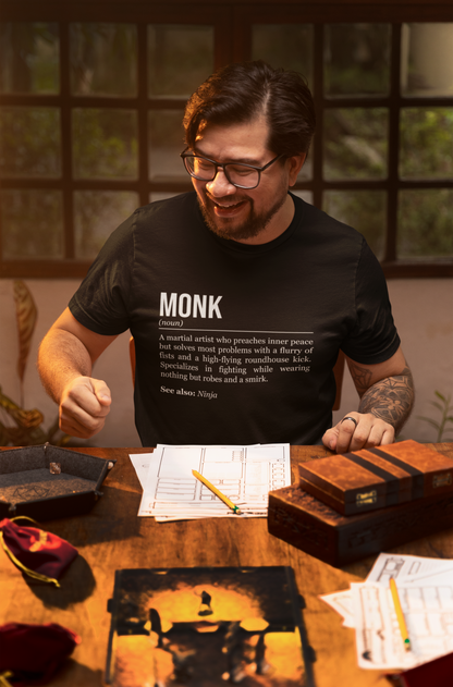 A man playing an RPG at a table, wearing a black monk T-shirt showing the definition of the class Monk. 
